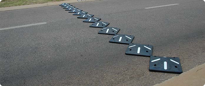 Black square speed bumps with white markings on the road for traffic management.
