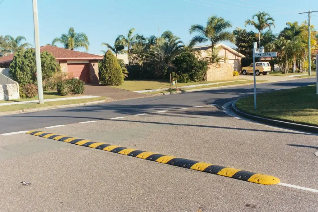 A black and yellow safety speed bump installed on the road for traffic-calming purposes.