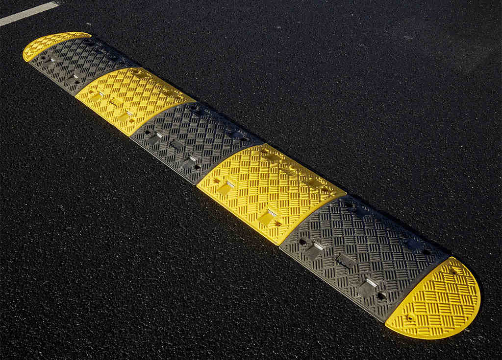 A black and yellow speed bump used to reduce vehicles' speed.