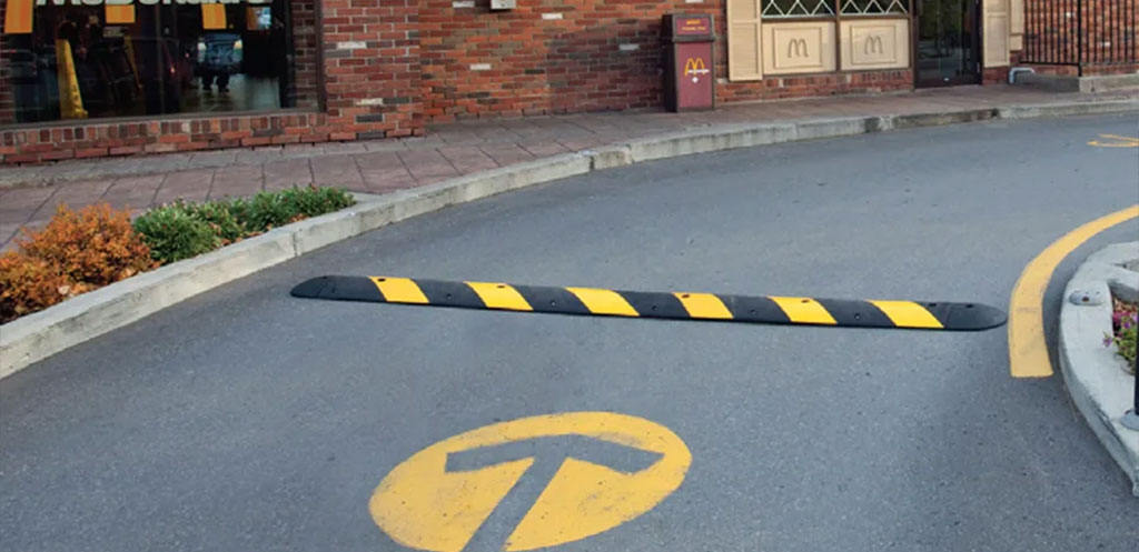 A black and yellow speed bump on a curve for traffic-calming purposes.