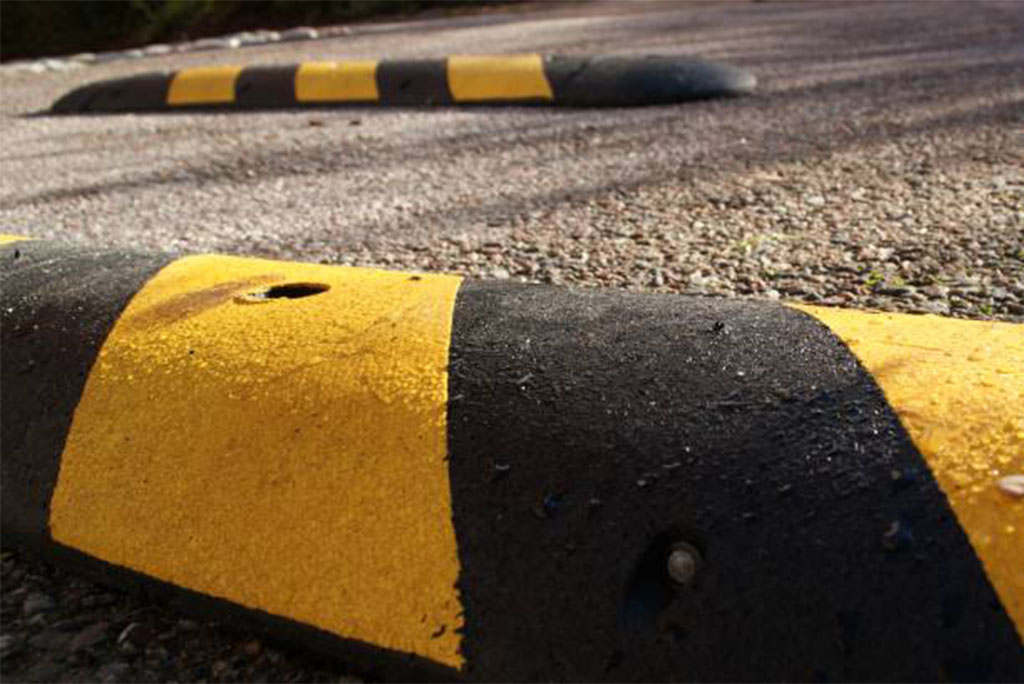 Black and yellow speed bumps on the road to reduce speed.