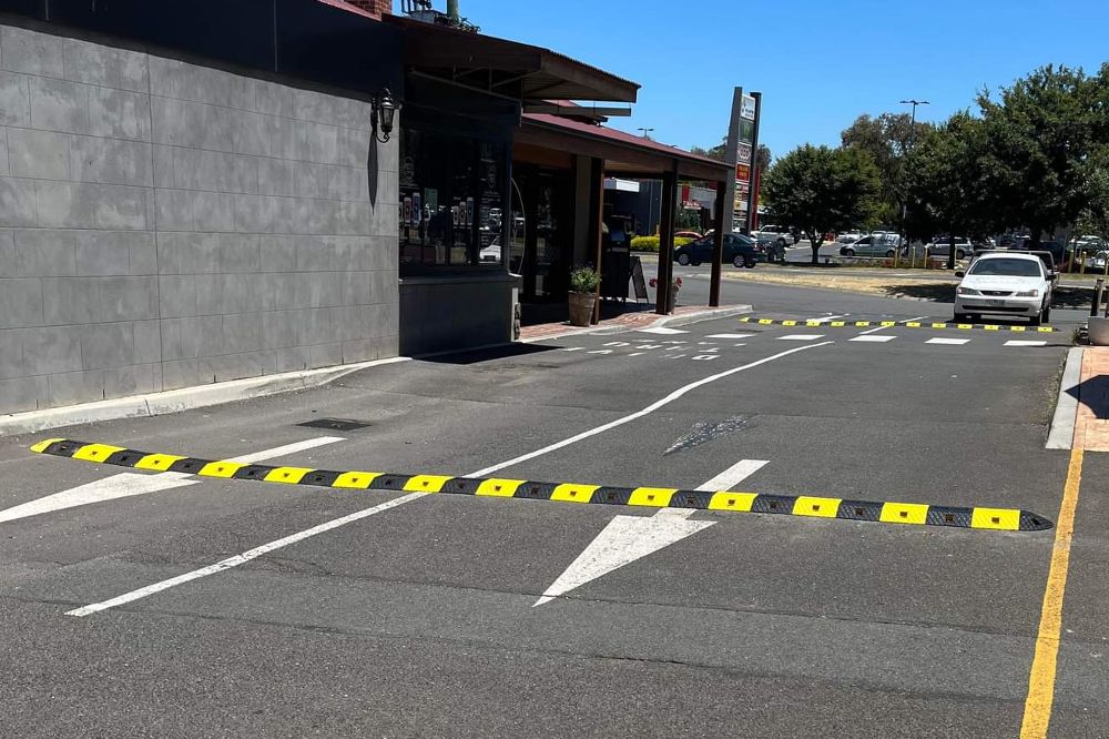 Black and yellow speed bumps on the road to reduce speed.