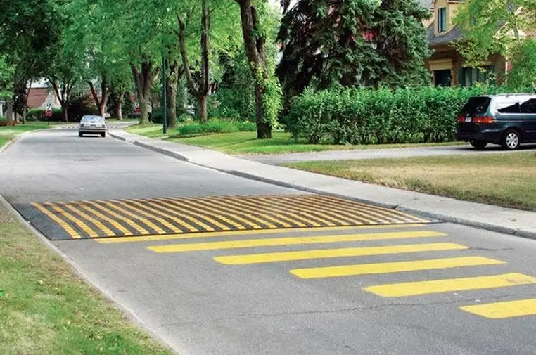 A black and yellow speed table on the road as traffic-calming tools.