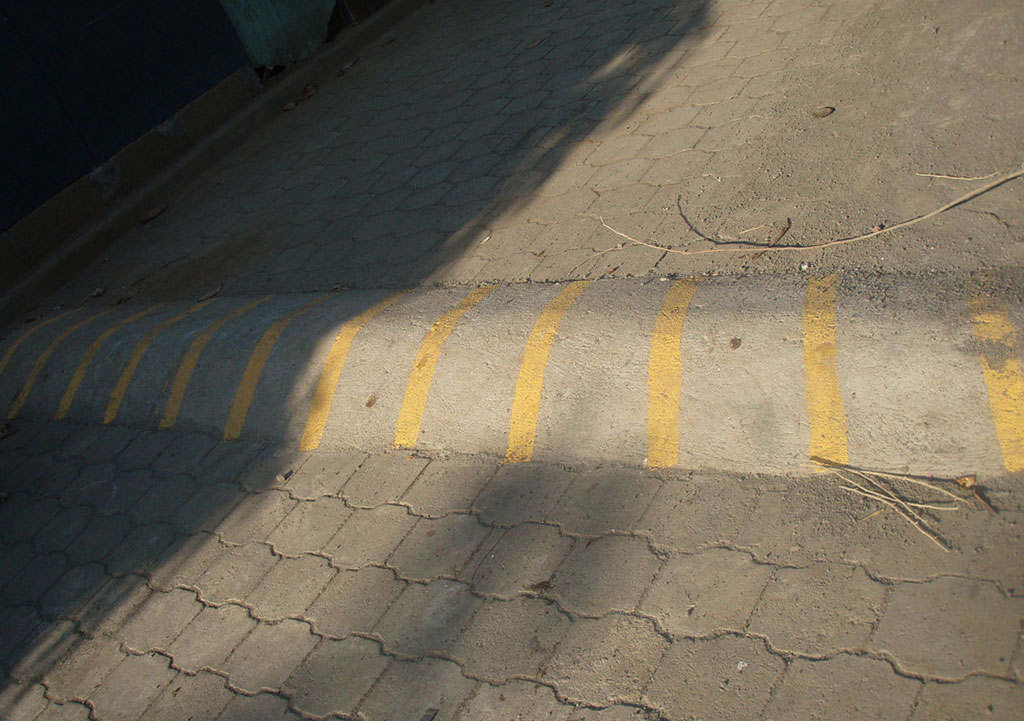 A concrete speed bump with yellow markings.