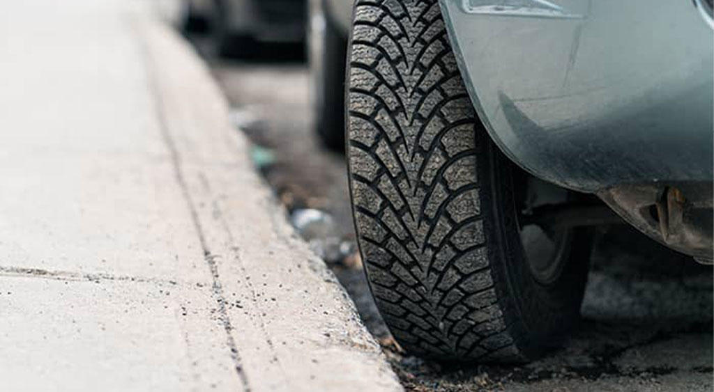 Car wheels are approaching the curb.