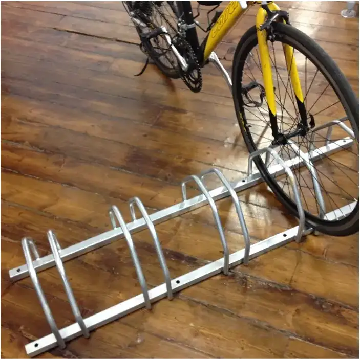 A steel floor cycle rack with a yellow bike parking on it.