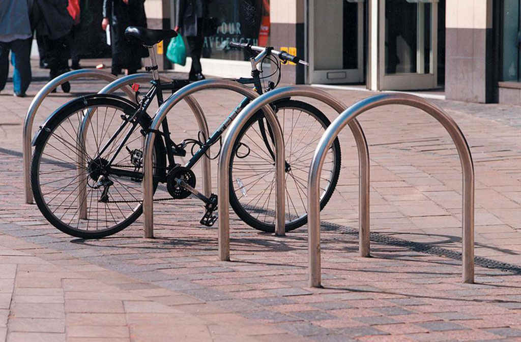 Harrogate cycle racks mounted on the ground, with a black bicycle parked on one of them.
