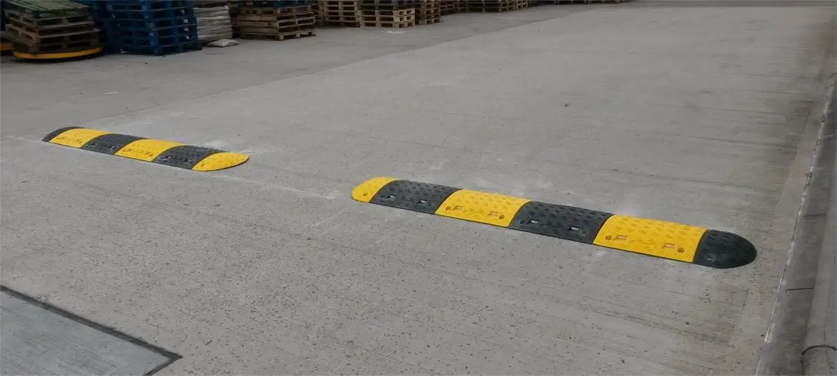 A pair of black and yellow speed bumps on the road to reduce speed.