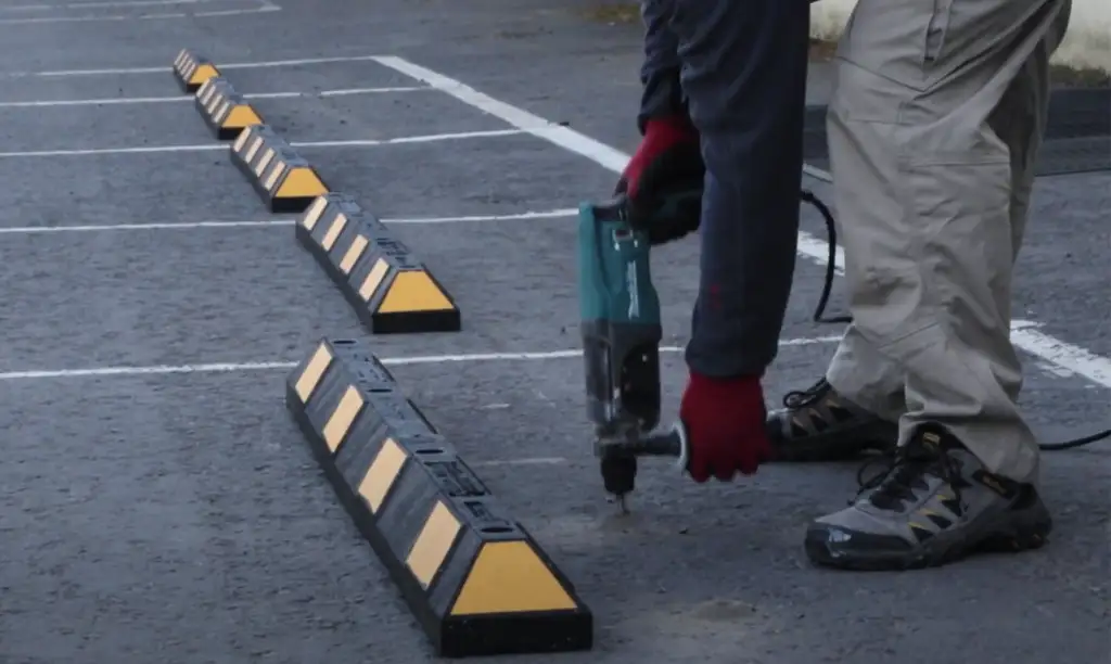 Black parking blocks with yellow stripes are being installed.