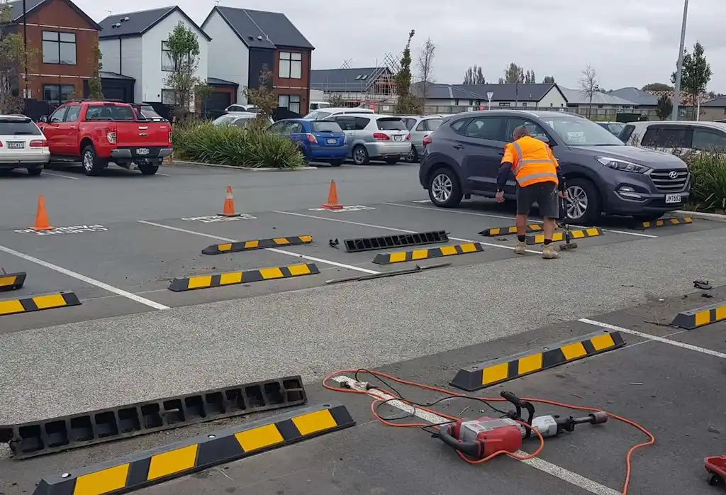 Black parking stops with yellow reflective films are being installed in the car park.