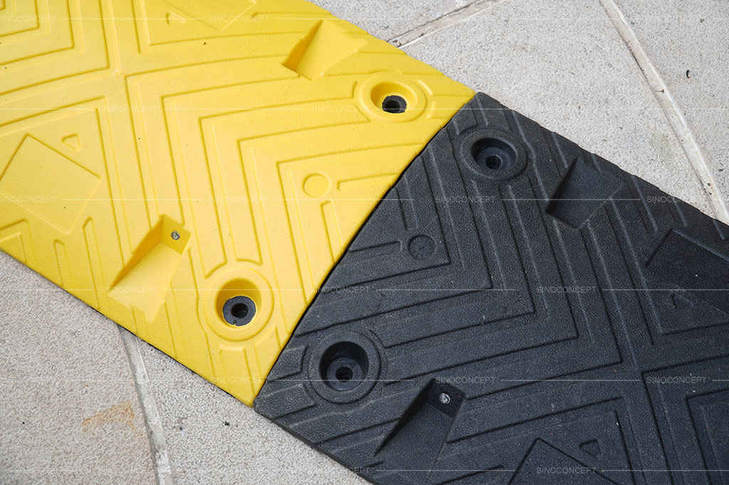 A black and yellow speed bump made of plastic-rubber composite material.