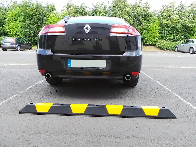 A black and yellow wheel stop made of plastic for parking management.