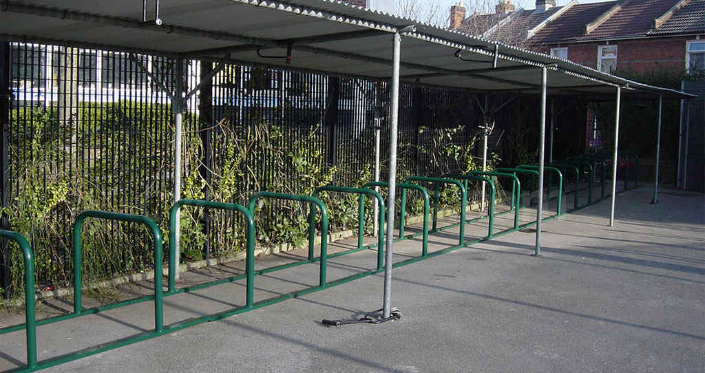 Green rail bike racks mounted on the ground for bicycle parking.