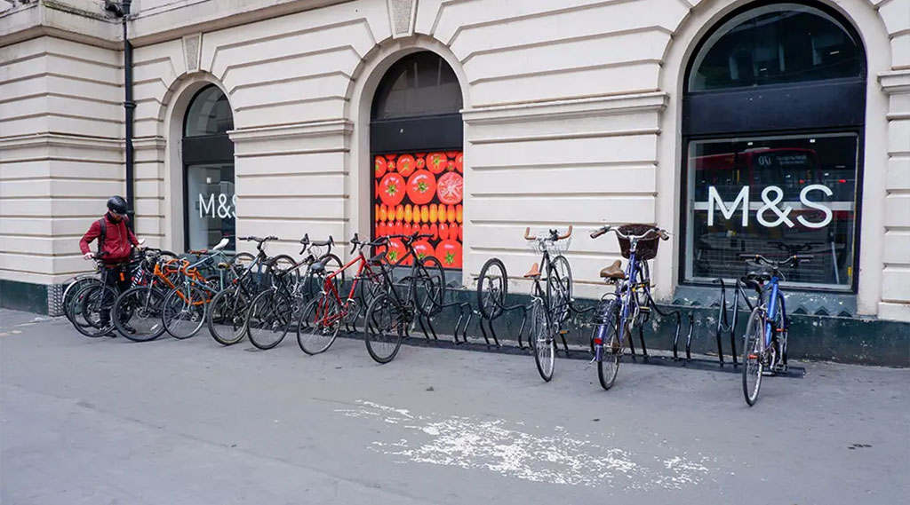 A black rail-mount bike rack with many bicycles parked on it.