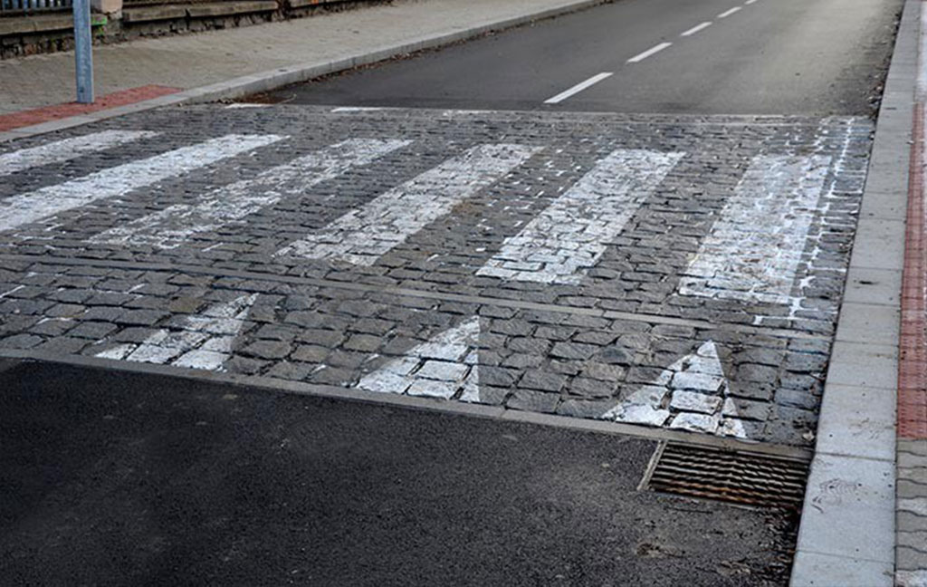 A raised crosswalk with white markings to ensure pedestrians' safety.