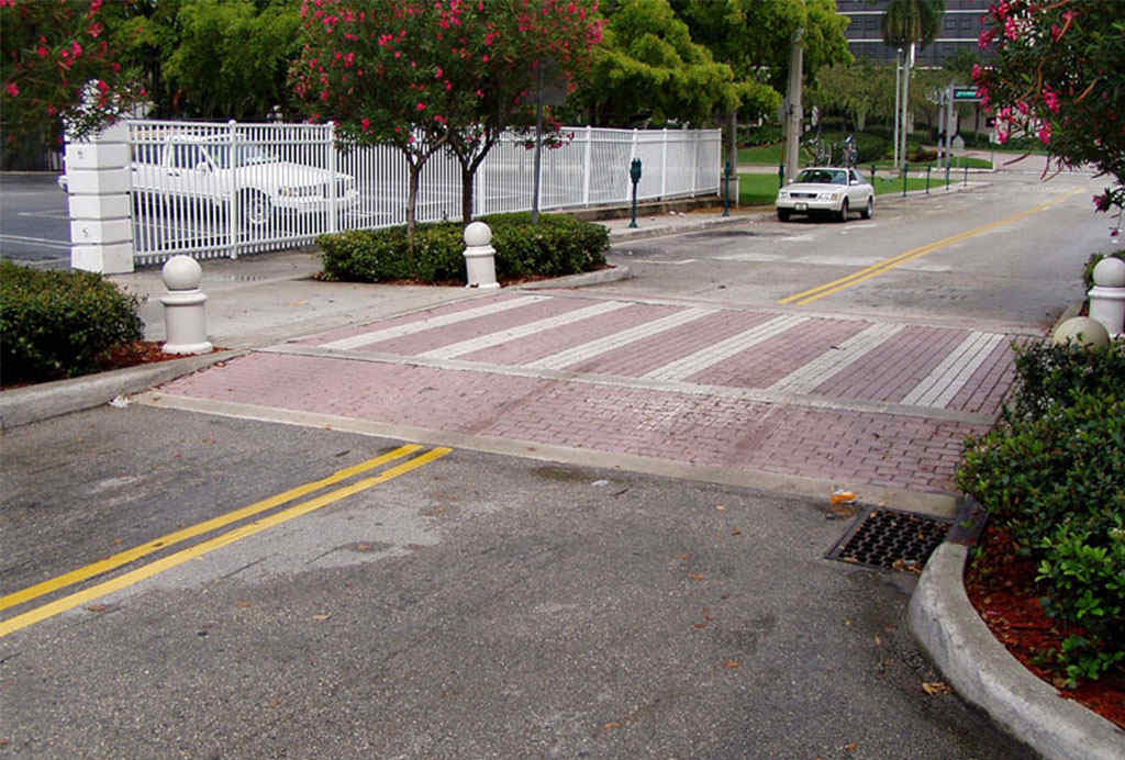 A red raised crosswalk with white markings to enhance pedestrians' safety.