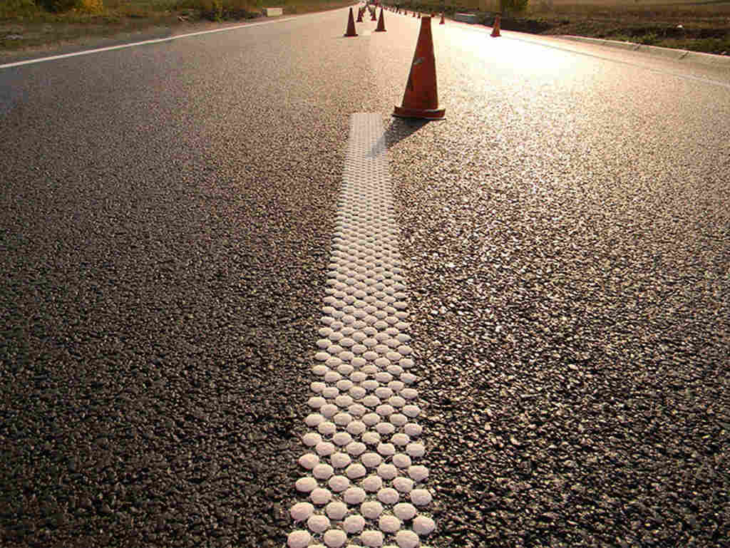 Raised rumble strips of round shape and white colours used as a traffic-calming measure.