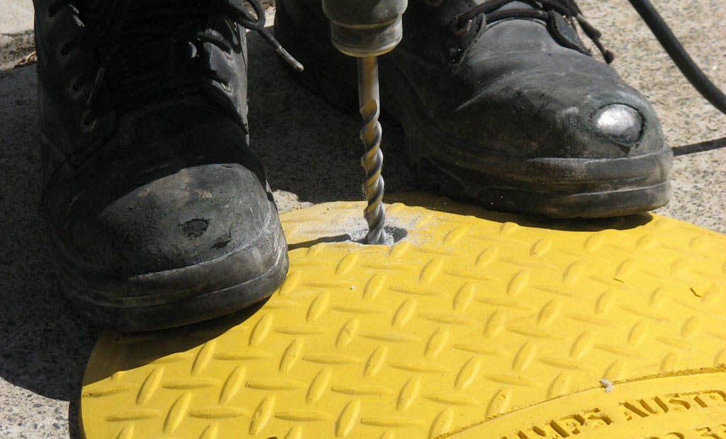 A speed bump is being installed with an electric drill.