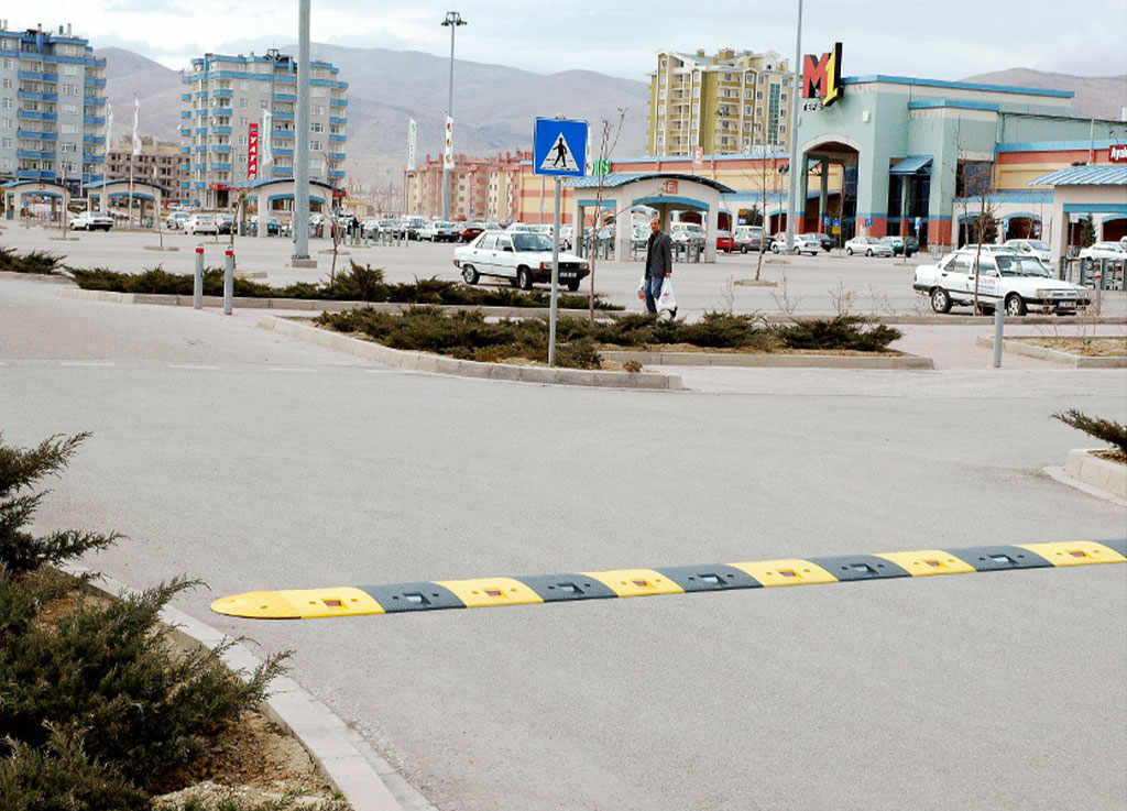 A road bump of black and yellow on the road to reduce speed.