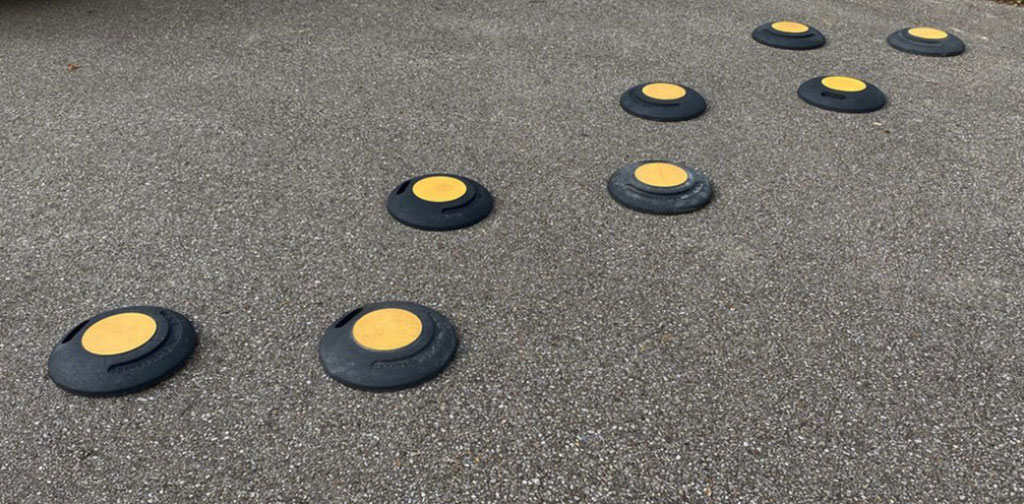 Rubber circular speed bumps on the road as a traffic-calming measure.