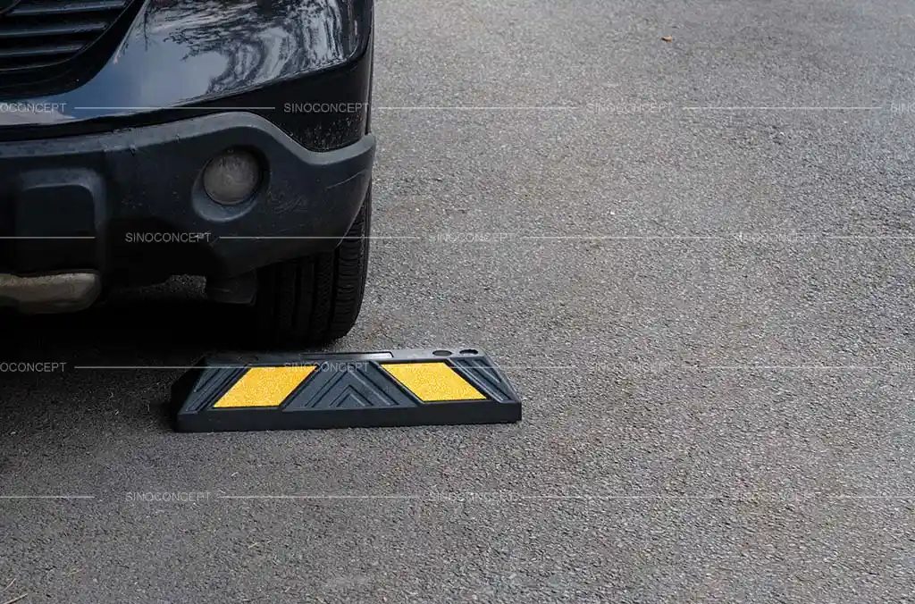 A black rubber parking kerb with yellow reflective films used for car park management.