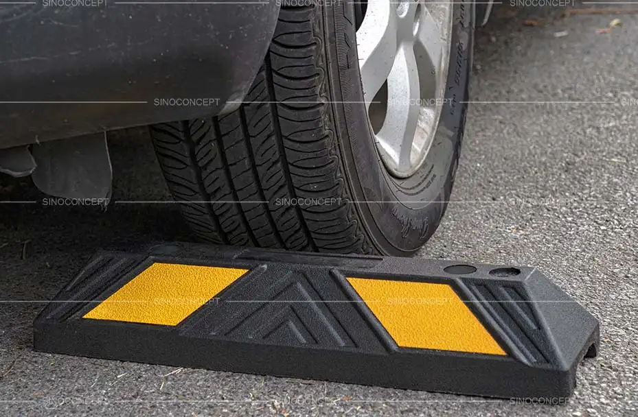 A black rubber parking stop with yellow reflective films for parking management.