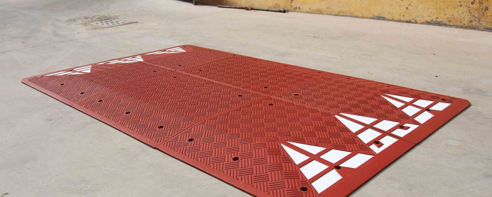 Rubber speed cushion coloured in red and pasted with white reflective films to be used for traffic calming purposes.