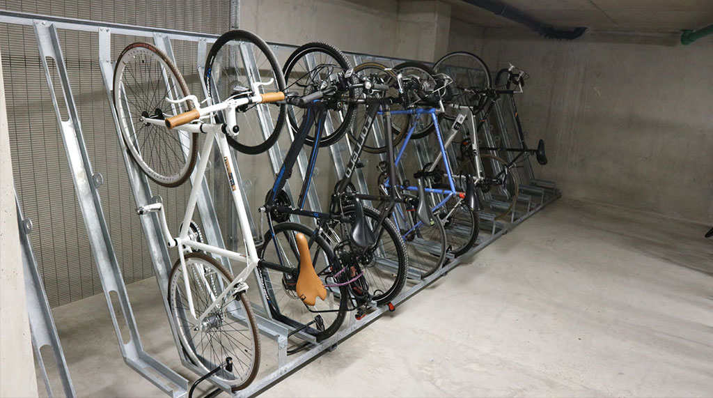 Semi-vertical bike stands installed against the wall to store bicycles, which make the most of the available space.