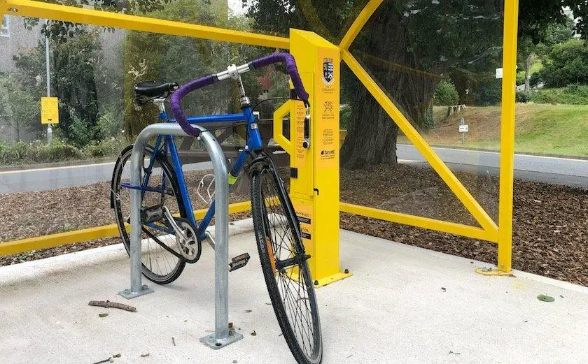 A Sheffield bicycle rack with a rail underneath, with a dark gray bike parked on it.