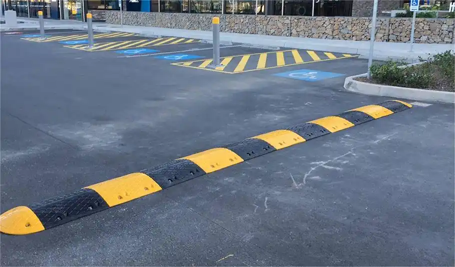 A black and yellow speed bump on the road to reduce speed.