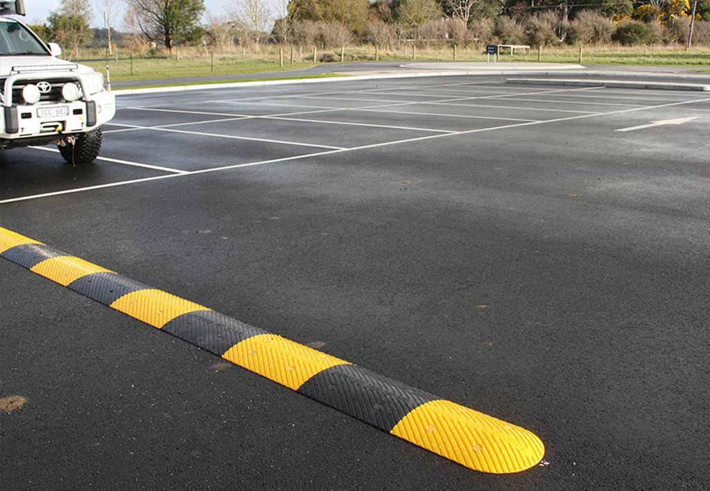 A black and yellow speed bump installed in a car park to reduce speed.