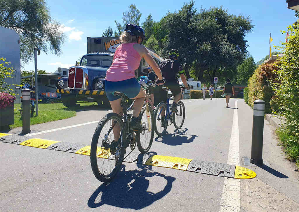 Some cyclists are riding over a black and yellow speed bump.