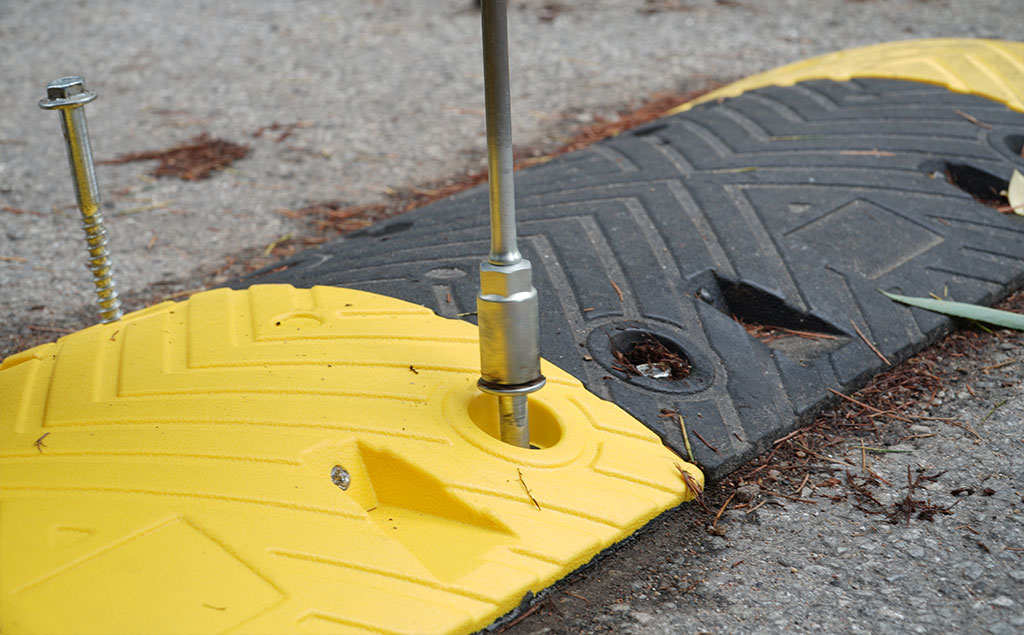 A black and yellow speed bump is being installed.