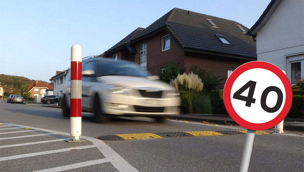 A black and yellow speed bump installed next to a speed limit sign indicating 40.