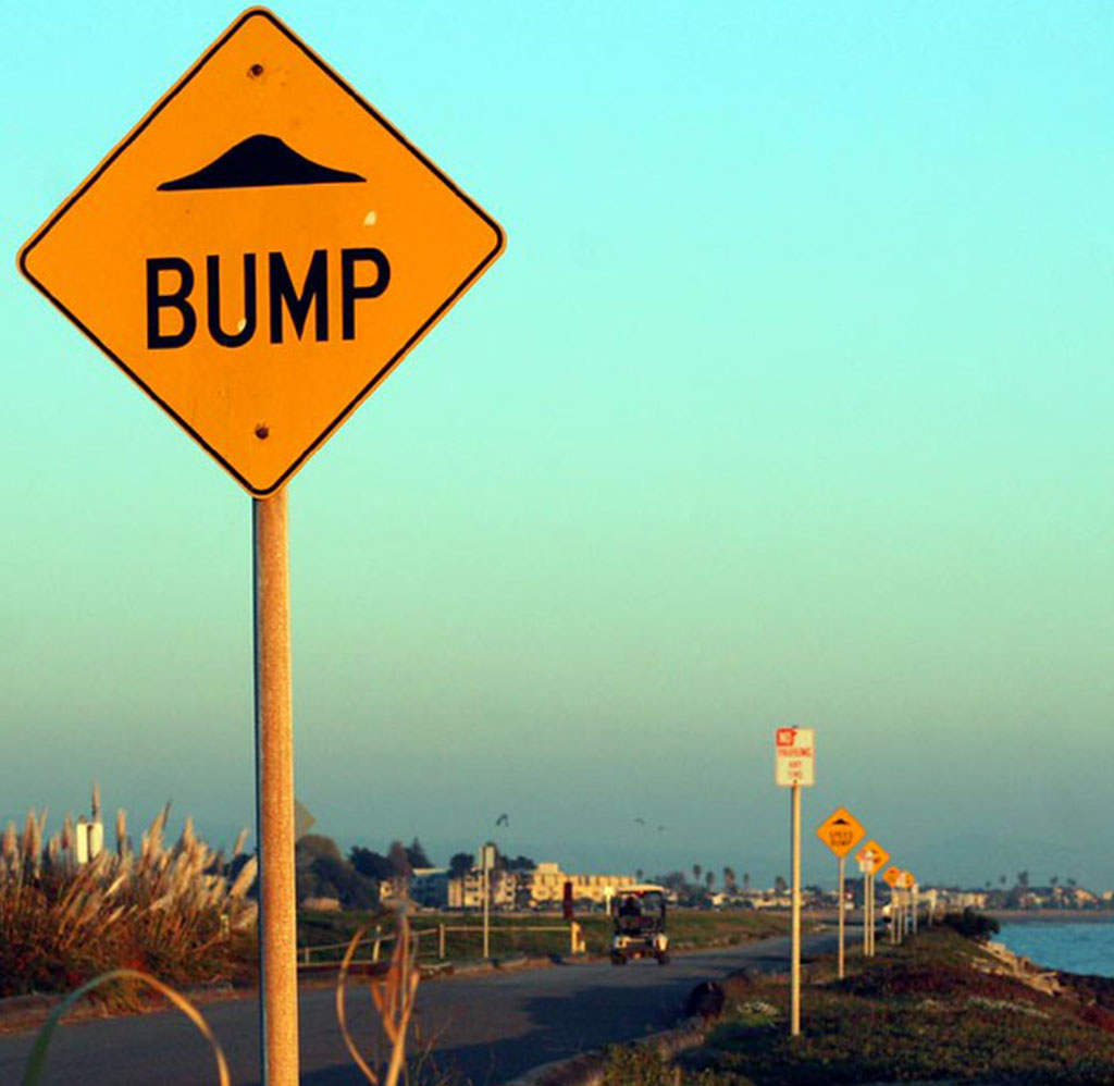 A speed bump traffic sign with yellow background.