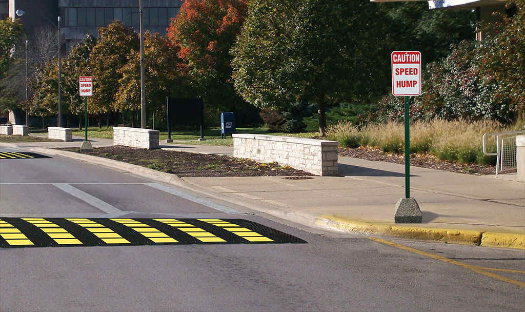 A black and yellow speed hump on the road to reduce speed.