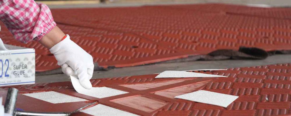 A worker is pasting white reflective films onto the rubber speed table to make it highly visible to drivers.