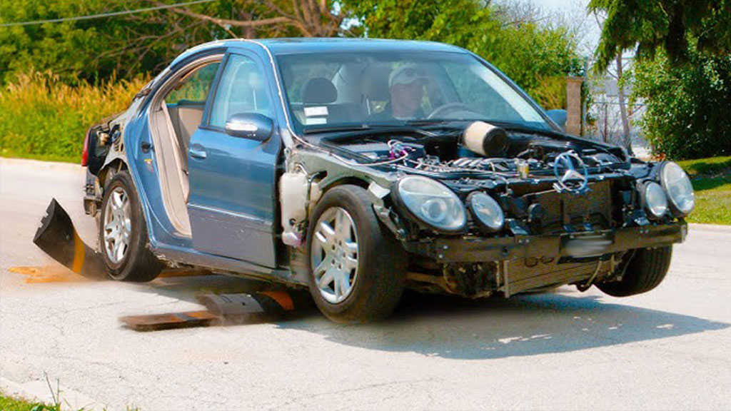 A speeding black car is passing two black and yellow speed bumps.