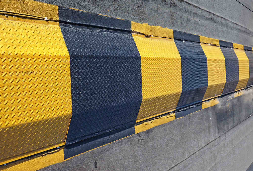 A black and yellow steel speed bump of high visibility.