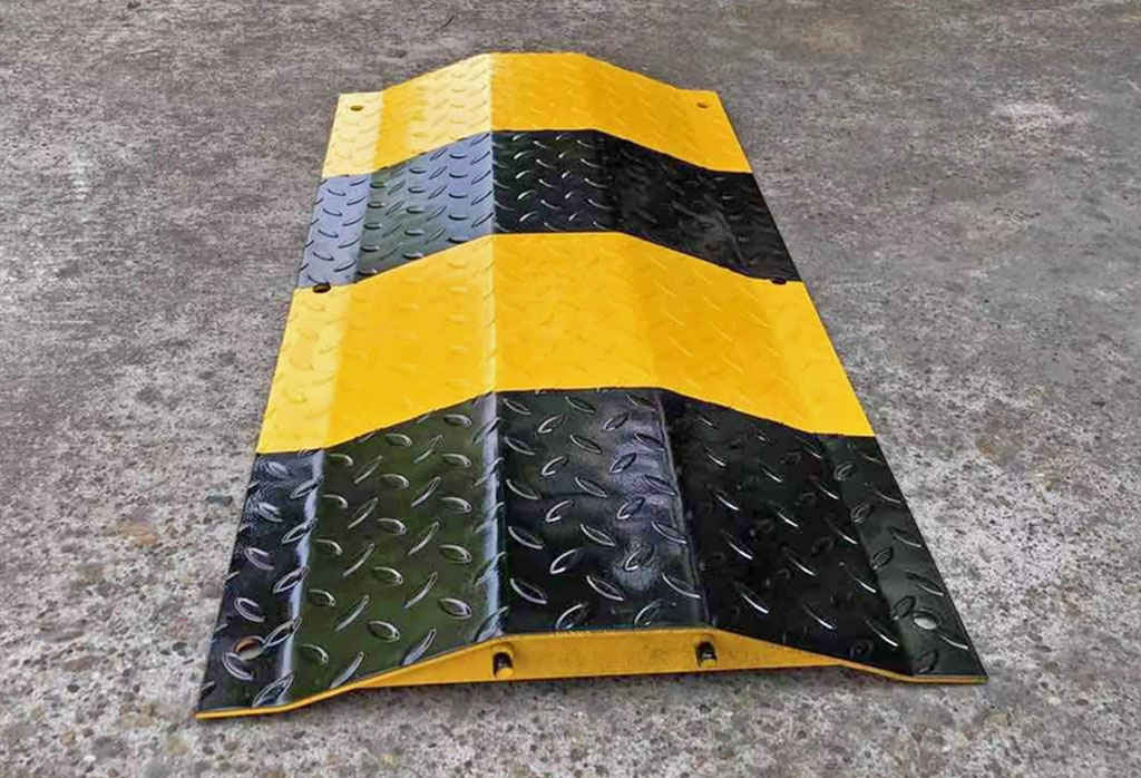 A black and yellow speed bump made of steel used to reduce speed.