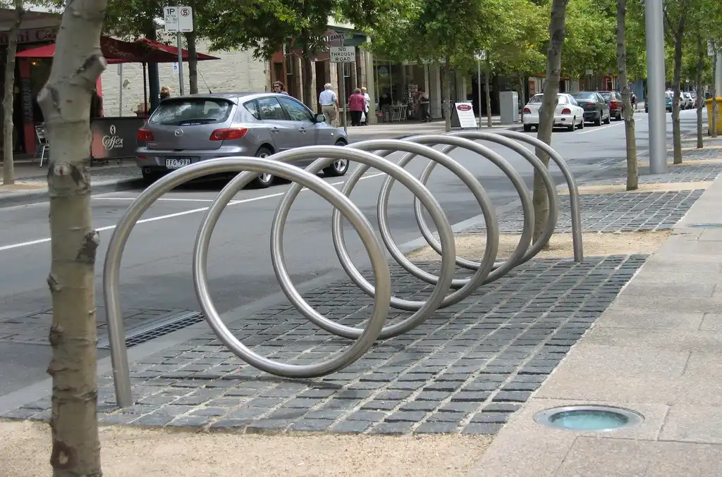 A steel spiral bike rack mounted on the ground for outdoor bike parking.
