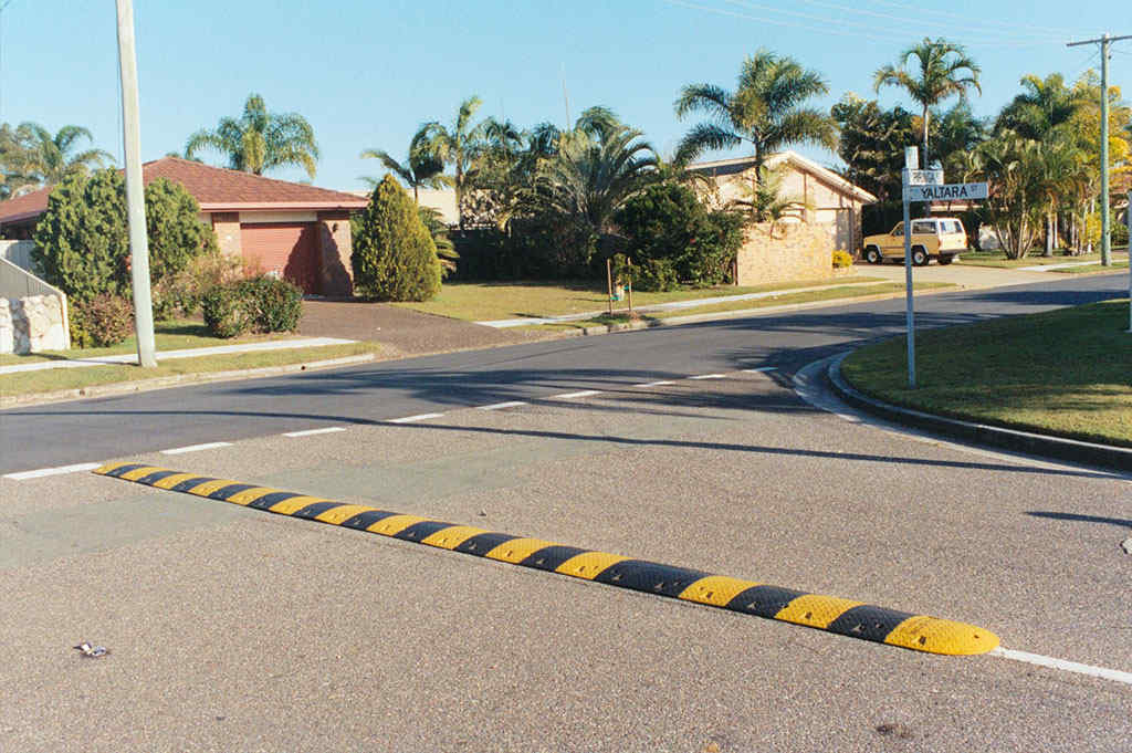 A black and yellow speed bump used for traffic-calming purposes.