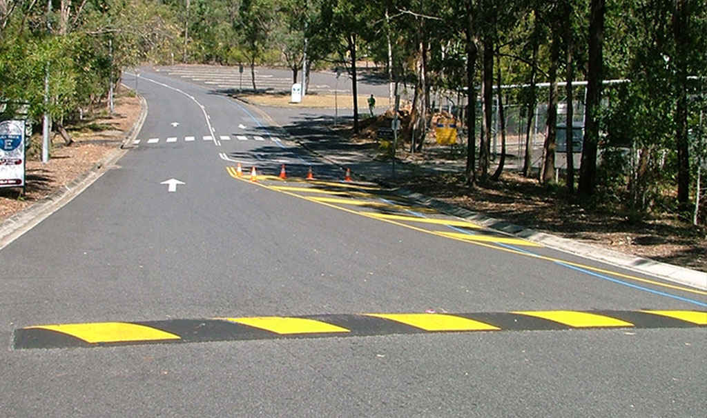 A black and yellow traffic speed bump on the road to enhance safety.