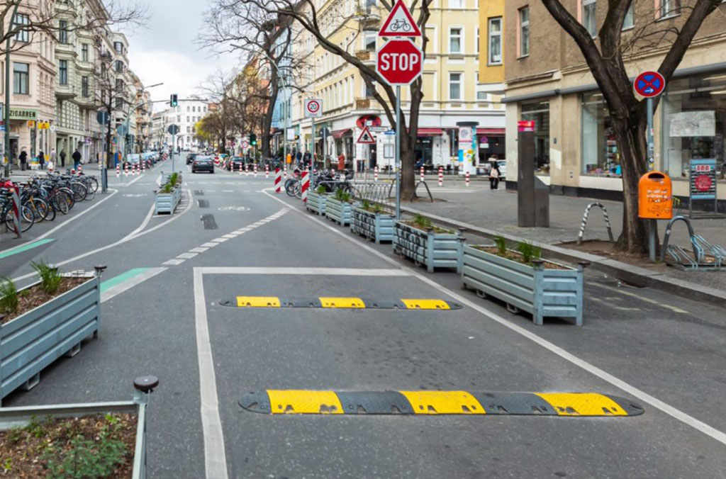 Two black and yellow speed bumps on the road for traffic-calming purposes.