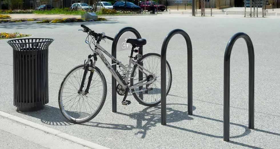 Three black U-shaped bicycle racks designed to securely park and lock bicycles in public spaces.