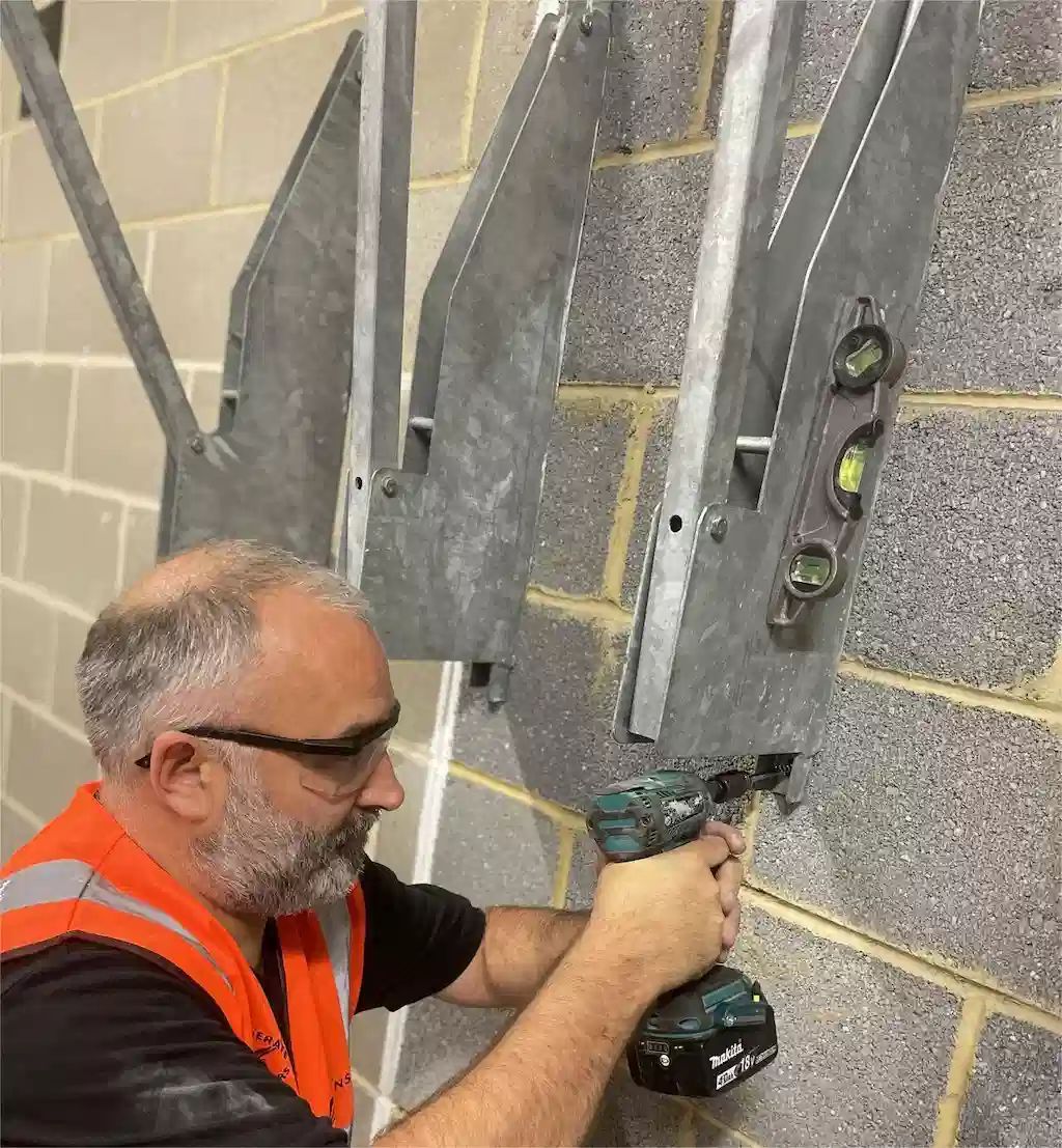 A man is installing a steel wall-mounted bike rack.