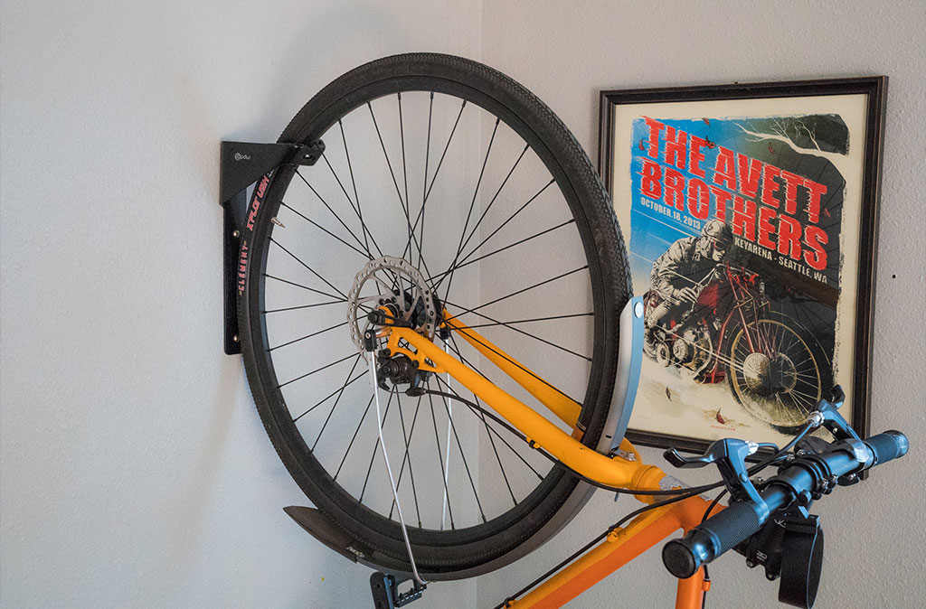 An orange bicycle is placed on a wall-mounted bike rack.