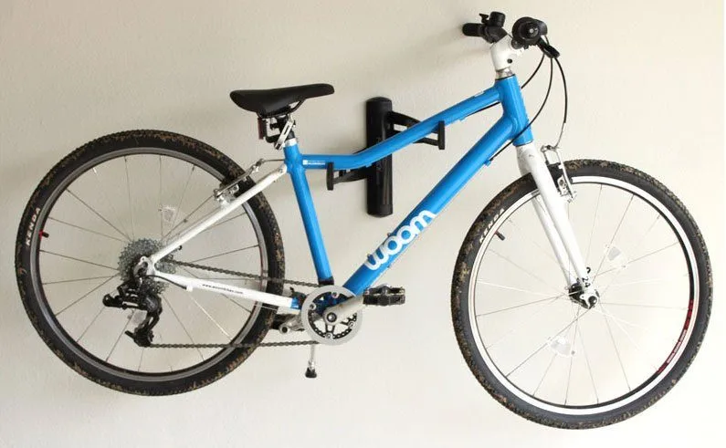 A black wall-mounted bike rack with a sky-blue bicycle hanging on it.