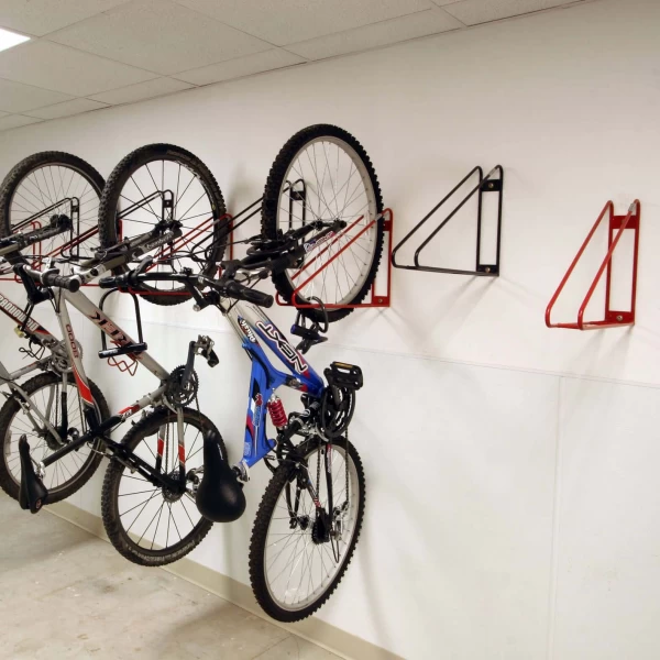 Black and red wall-mounted bike racks with several bike hanging on them.