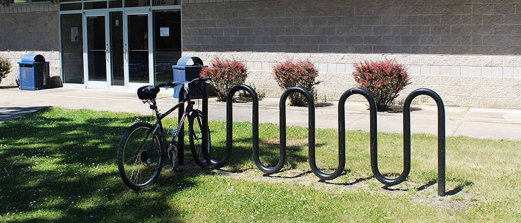 A black wave-style cycle rack installed on the grass for bike parking.